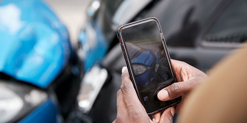 close up of a man's hands taking photo of a car accident